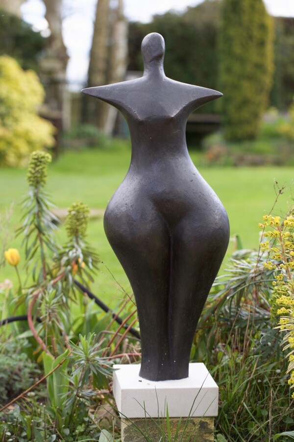 contemporary bronze sculpture of a standing abstract figure in a garden
