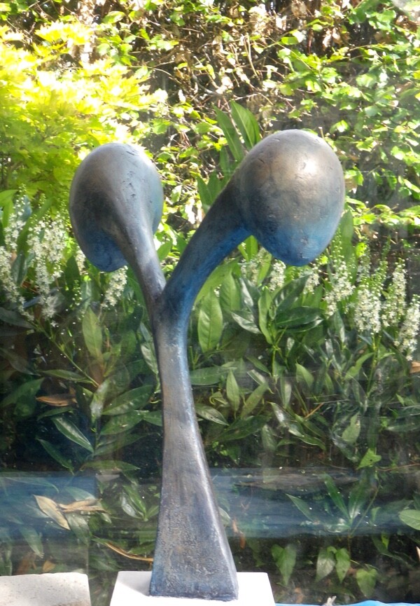 Ceramic blue sculpture of two fruits pulling into opposed directions