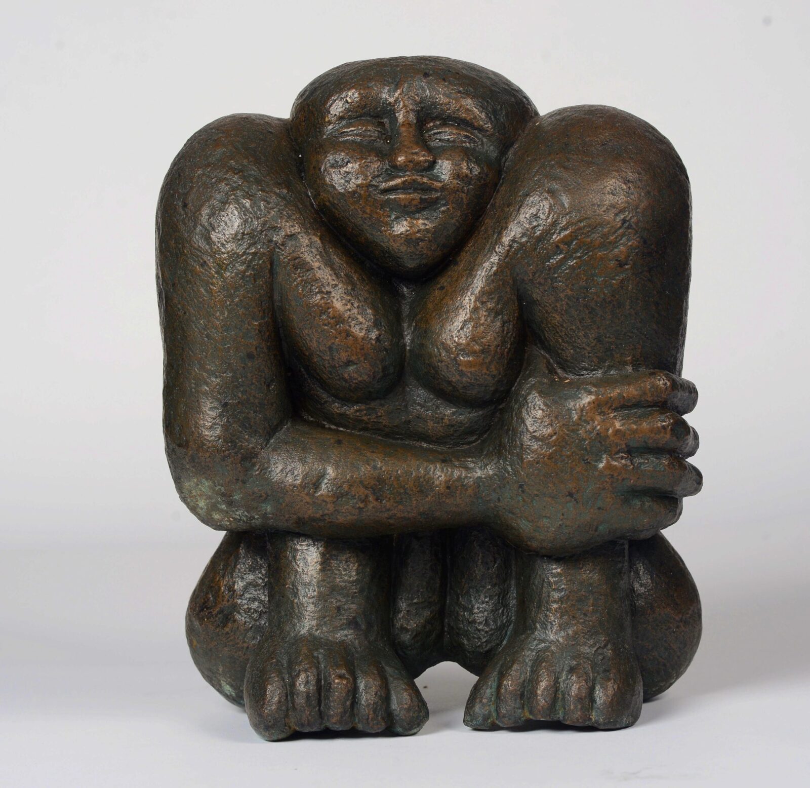 modern bronze sculpture of a compact sitting figure