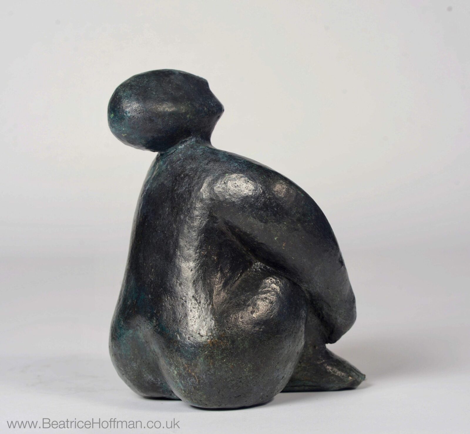 small modern bronze sculpture of a sitting figure for the home