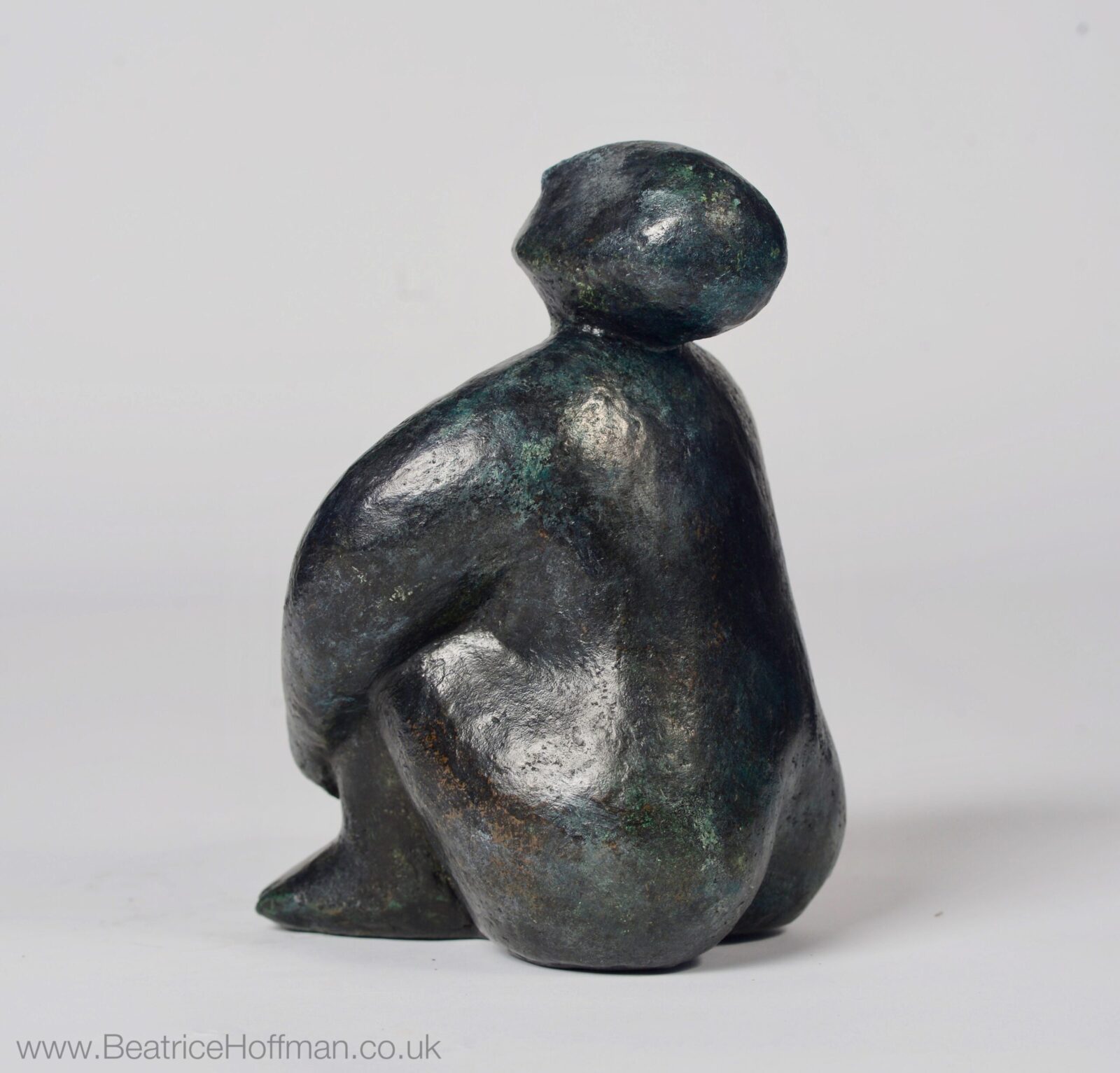 small modern bronze sculpture of a sitting figure for the home
