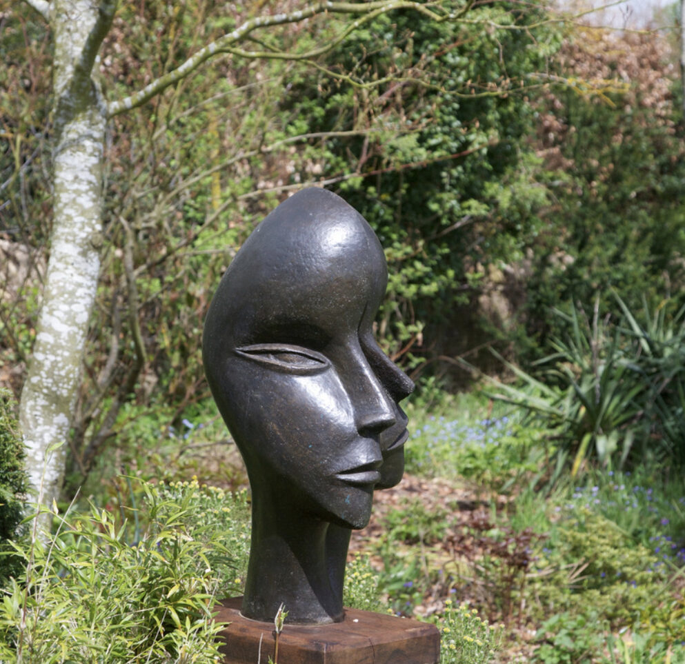 contemporary bronze sculpture of double head installed in the garden