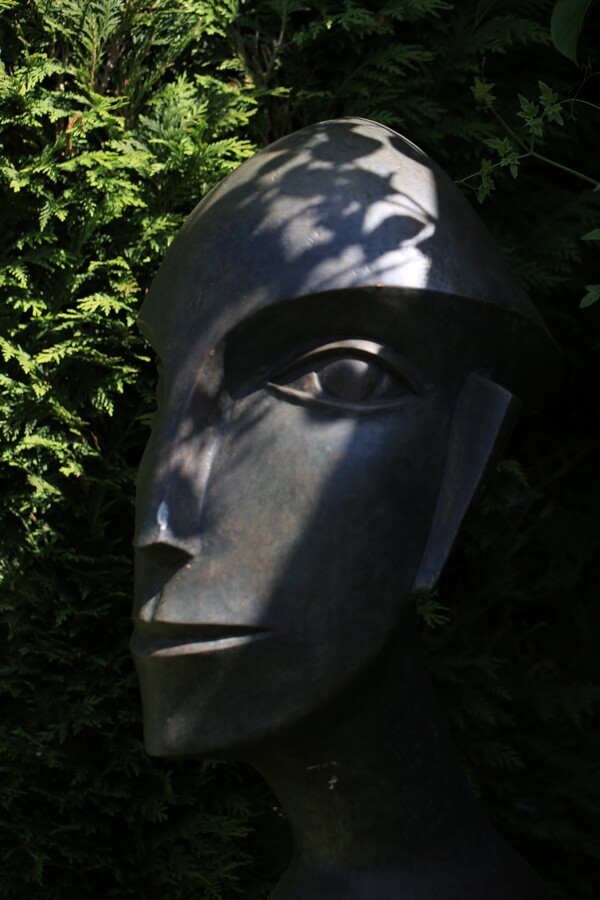 Abstract bronze sculpture of a modern cubist head in the garden