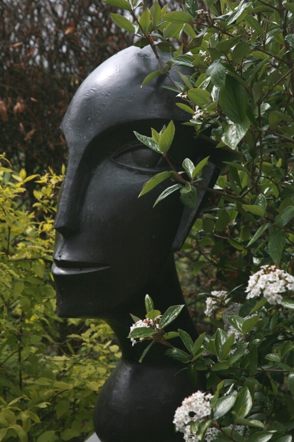 Abstract bronze sculpture of a modern cubist head in the garden
