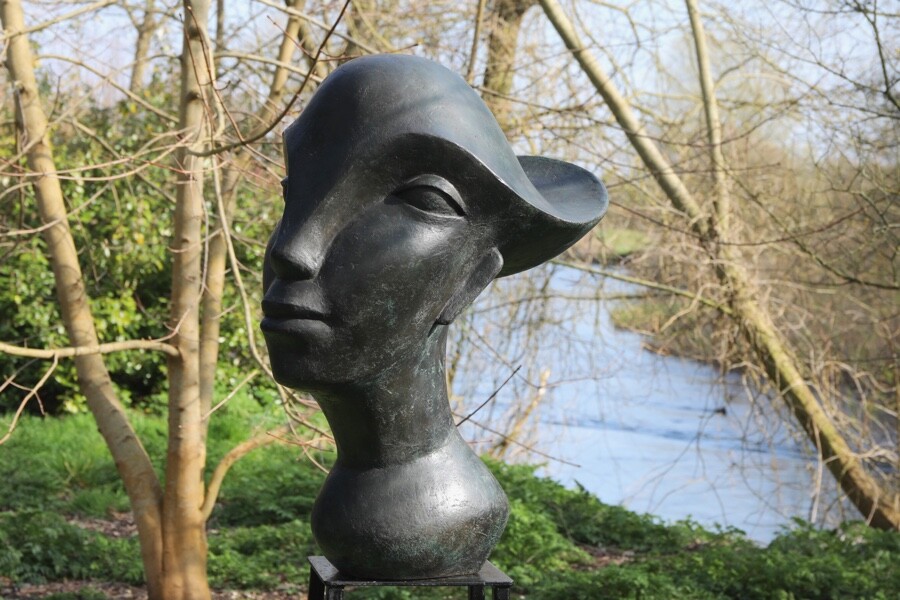 Contemporary abstract bronze garden sculpture of a head with flowing hair