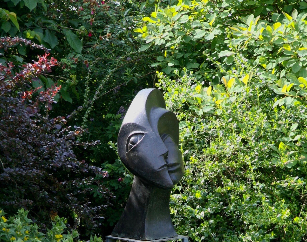 bronze sculpture Sun and Moon surrounded by bushes in the garden